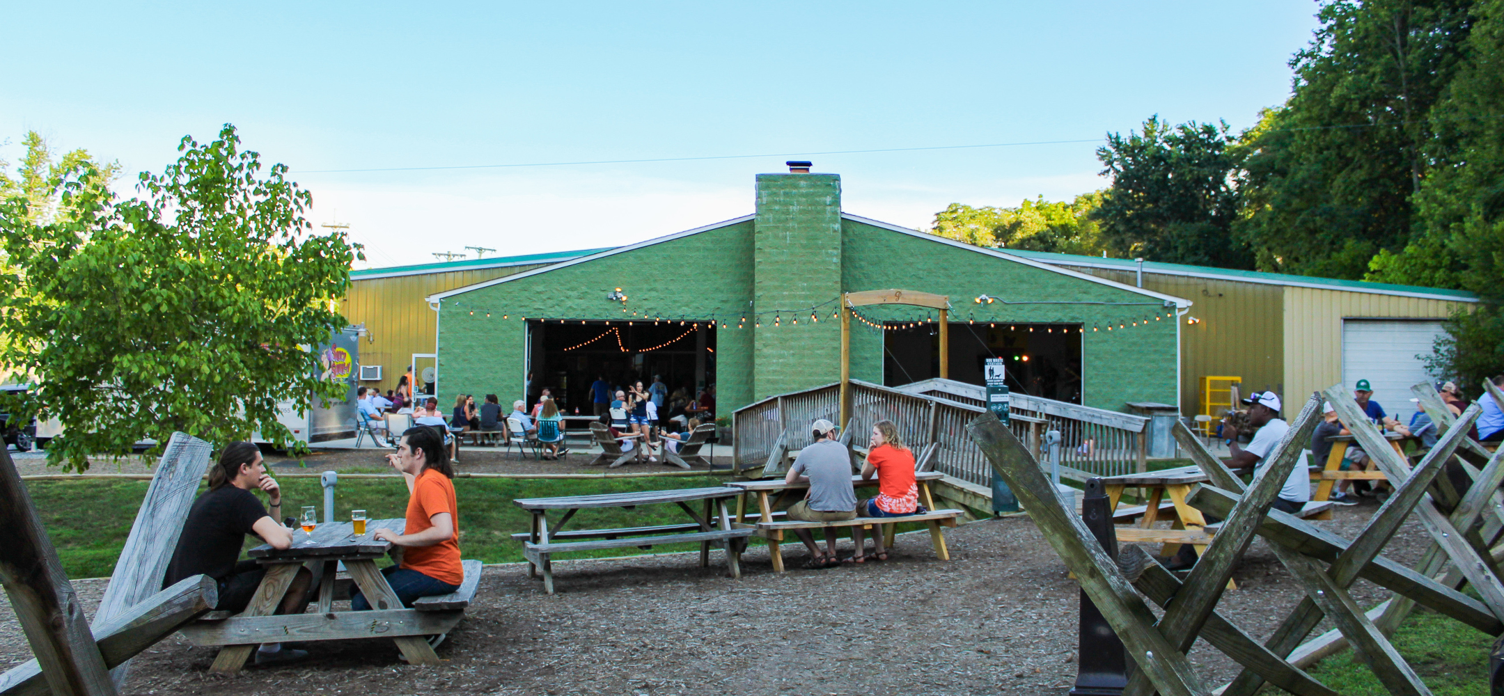 Outside of a green barn with picnic tables in front