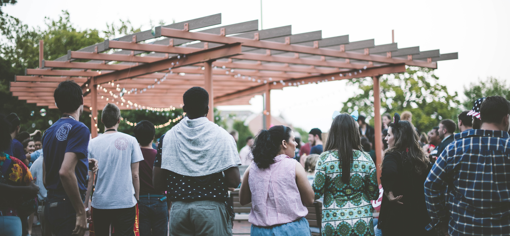 People standing outdoors near a pergola