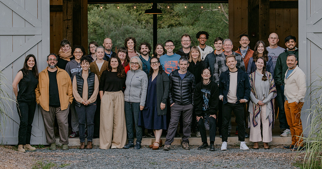 A group photo of 30 people gathered in front of a barn.