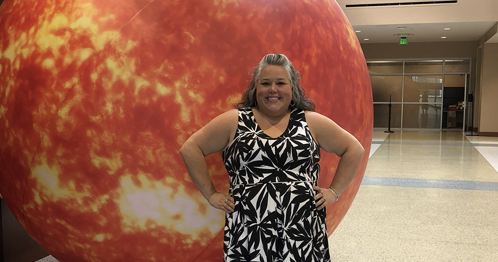 Susan Turner posing with hands on hips in front of model of the sun.